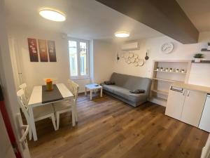 a kitchen and a living room with a table and a couch at Jolly -Center Bright Apartment at Tartini Square in Piran