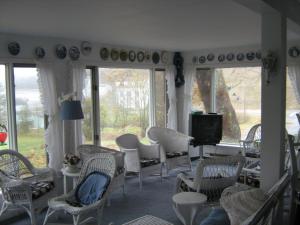 a living room with chairs and a tv and windows at The Olde Village Inn in Centreville