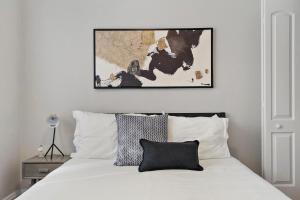 a bedroom with a white bed with a picture above it at 1BR Calm & Cozy Apt in Lincoln Square - Eastwood 2S in Chicago
