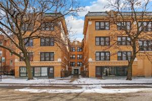 a large brick building with trees in front of it at 1BR Calm & Cozy Apt in Lincoln Square - Eastwood 2S in Chicago
