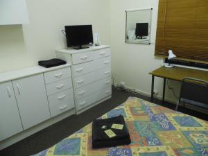 1 dormitorio con 1 cama y vestidor con TV en Star Inn Accommodation, en Mount Isa
