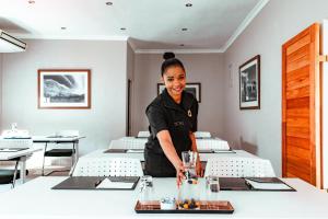 タルバにあるTulbagh Boutique Heritage Hotelのレストランのテーブルの後ろに立つ女 +84枚の写真