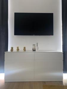 biała komoda z telewizorem z płaskim ekranem na ścianie w obiekcie Pvteoli Suite w mieście Pozzuoli