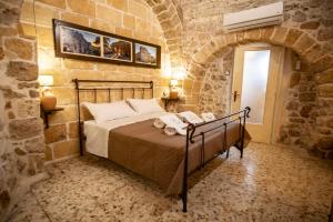 a bedroom with a bed in a stone wall at DOMUS CESARE - dimora storica totalmente in pietra nel cuore del centro storico con cabina doccia pietra in camera e zona relax esterna-historic residence entirely made of stone in the heart of the historic center with stone shower cabin in the room in Carovigno
