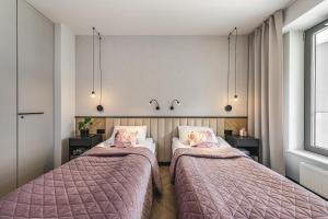 two beds with pink blankets in a room at Apartament Moje Miasto in Gdynia