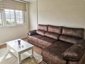 een woonkamer met een bruine bank en een tafel bij APTO. SANXURXO in Camariñas