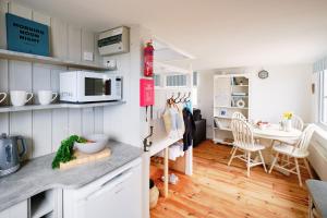 a kitchen with white cabinets and a dining room at Gwithian, Sea Dream Beach Chalet in Gwithian
