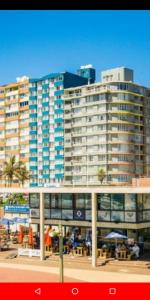 a large building with tables and umbrellas in front of it at Sandz accomodation at 108 in Durban