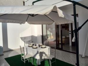 a white table with chairs and an umbrella at B&B del Centro in Veglie