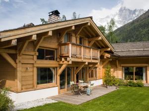 Cette grande maison en bois dispose d'une terrasse et d'une table. dans l'établissement Les Chalets des Liarets, à Chamonix-Mont-Blanc