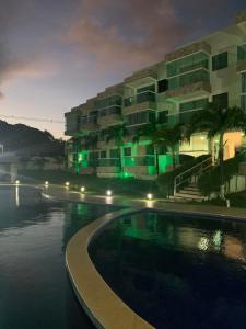 a swimming pool in front of a building at night at Residêncial mar e sol in Conde