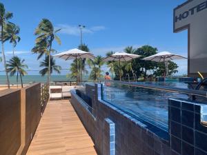 uma piscina com guarda-sóis ao lado de uma praia em Netuanah Praia Hotel em João Pessoa