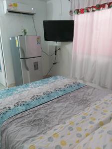 a bed in a room with a refrigerator and a window at Casa ITCI Tours in Cartagena de Indias