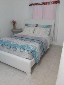 a white bed with a blue comforter in a bedroom at Casa ITCI Tours in Cartagena de Indias