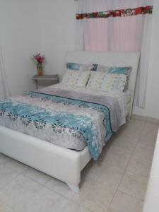 Una cama blanca con una manta azul y blanca. en Casa ITCI Tours en Cartagena de Indias