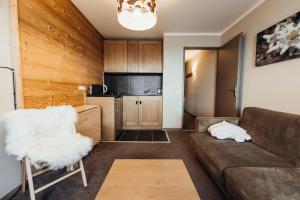 a living room with a couch and a kitchen at Cosy studio with terrace and private parking in a quiet area in Megève