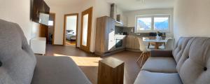 ein Wohnzimmer mit einem Sofa und einem Tisch sowie eine Küche in der Unterkunft Alpenlodge Pitztal in Wenns