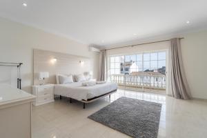 una camera bianca con un letto e una grande finestra di Villa Lemos by HelloVacations ad Albufeira