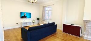 a living room with a blue couch and a tv at Marigold Villa in Harrow