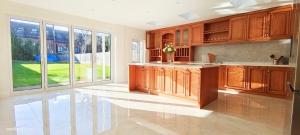 a large kitchen with wooden cabinets and a large window at Marigold Villa in Harrow