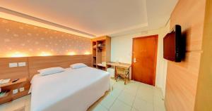 a bedroom with a white bed and a television at Amazon Plaza Hotel in Cuiabá
