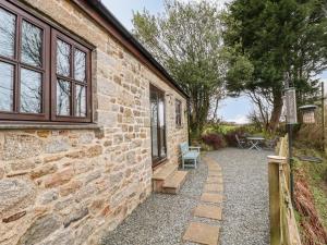 Casa de piedra con pared de piedra y patio en Brocks Barn, en Lanlivery