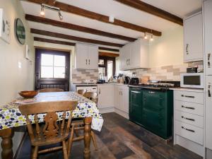 uma cozinha com armários brancos e uma mesa com cadeiras em 4 Mowhay Cottages em Saint Goran