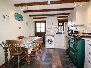 uma cozinha com uma mesa e um fogão forno superior em 4 Mowhay Cottages em Saint Goran