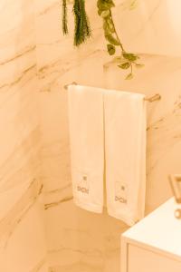 uma casa de banho com toalhas brancas penduradas numa parede em DCM LOFTS em Arcozelo