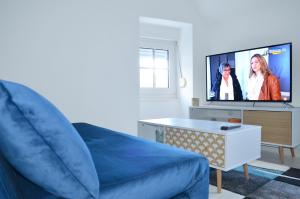 a living room with a couch and a flat screen tv at La Ferté-Macé, proche Hôtel de ville, Charmant T2 in La Ferté-Macé