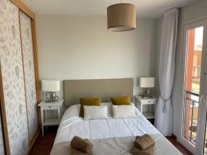 een slaapkamer met een wit bed, 2 tafels en een raam bij VILLA MARIE Agradable y tranquila MAISON con piscina in Corralejo
