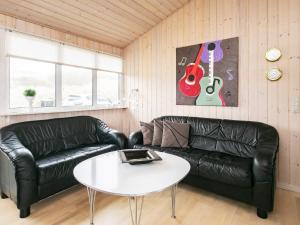 ブロックフスにある6 person holiday home in Blokhusのリビングルーム(黒い革張りのソファ、白いテーブル付)