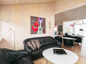 ブロックフスにある6 person holiday home in Blokhusのリビングルーム(黒い革張りのソファ、テーブル付)