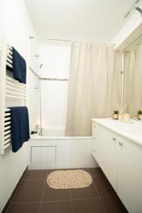 a white bathroom with a tub and a sink at Le Délicieux T2-42m2-Disney in Montévrain +8 photos
