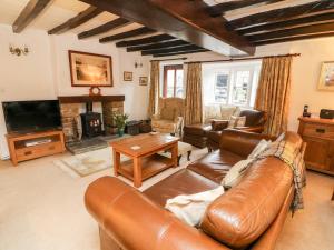 een woonkamer met een leren bank en een televisie bij Eastburn Cottage in West Burton