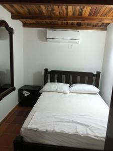 a bedroom with a white bed with a wooden ceiling at Hotel Boutique Casa Antigua in San Vicente de Chucurí