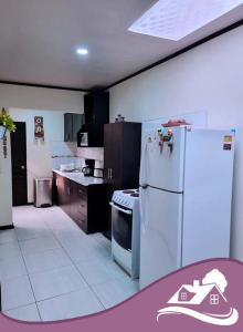 a kitchen with a white refrigerator and a stove at Casa Colima in Isla de Tibás