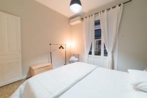 a white bedroom with a white bed and a window at Heart of Athens Thisio in Athens