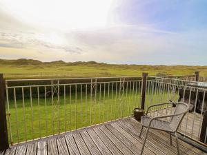 a deck with a chair and a view of a field at Ty'r Heulwen in Aberdyfi