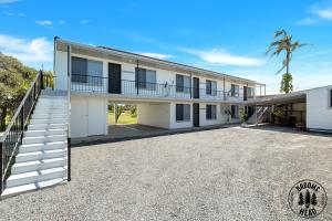 an exterior view of a white building with a driveway at Beachside at Brooms in Brooms Head