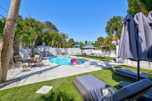 un patio trasero con piscina, mesa y sombrilla en The Ringling Beach House, en Siesta Key