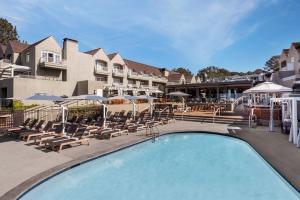 una piscina en un hotel con sillas y sombrillas en L'Auberge Del Mar Resort and Spa, en San Diego