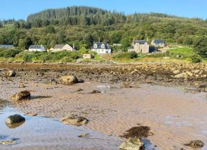a beach with rocks and houses in the background at The Neuk in Tighnabruaich