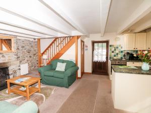 a living room with a green chair and a table at Swift Cottage in Mawgan in Meneage