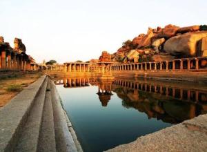 a body of water with a bridge and buildings at Gopi Guest House in Hampi