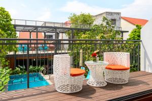 une terrasse avec trois tabourets et une table sur un balcon dans l'établissement SAVV HOTEL, à George Town