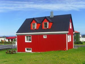 a red barn with a black roof on a field at Grundarfjördur Hostel in Grundarfjordur