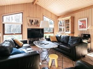 Torup Strandにある8 person holiday home in Fjerritslevのリビングルーム(黒革の家具、テーブル付)