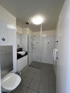 a bathroom with a toilet, sink, and shower stall at Country Roads Motor Inn Dysart in Dysart