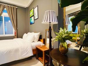 um quarto com uma cama e uma mesa com um candeeiro em Nhà An Đà Lạt em Da Lat